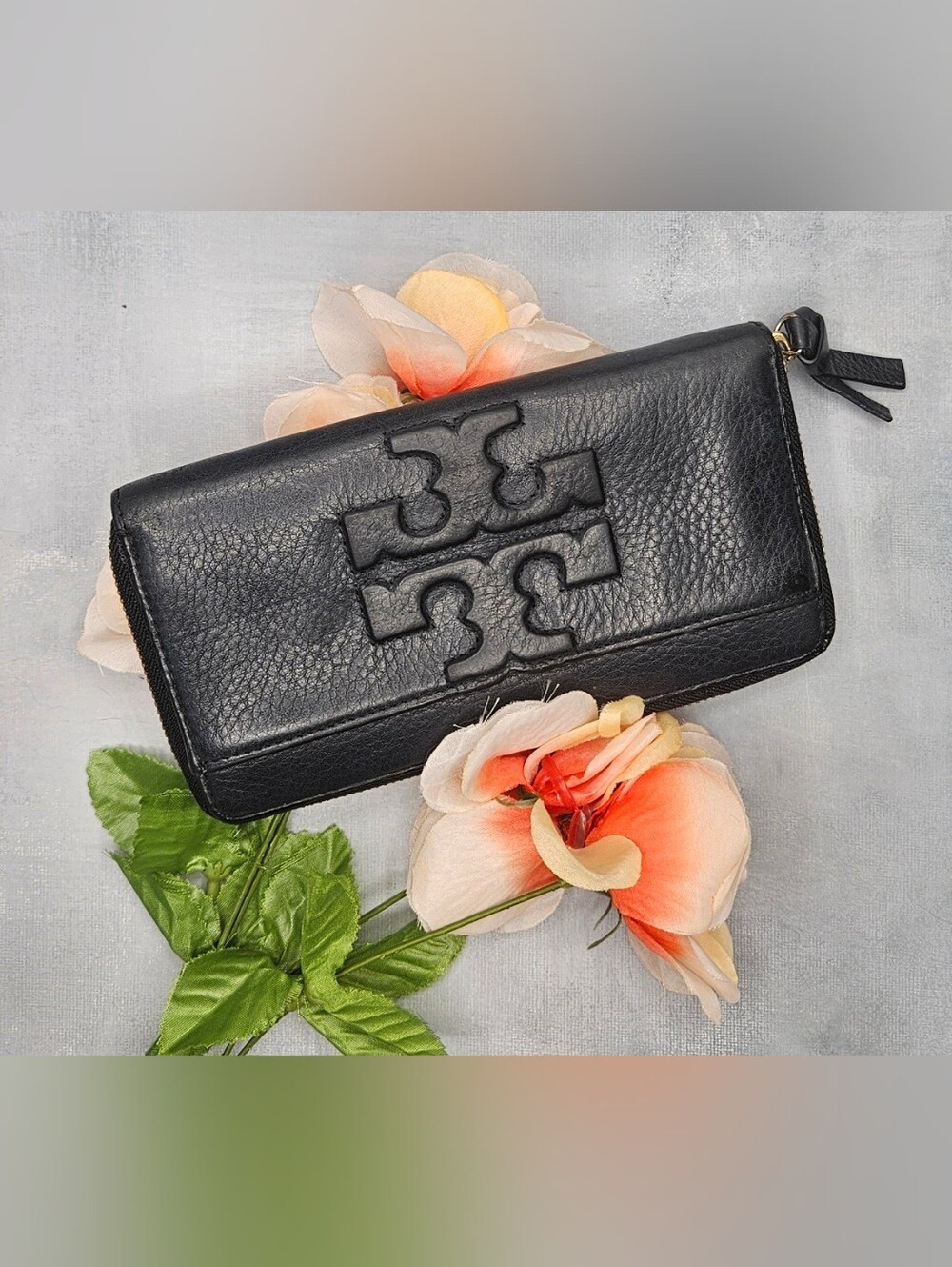 Tory Burch black continental wallet features a prominent embossed logo and leath